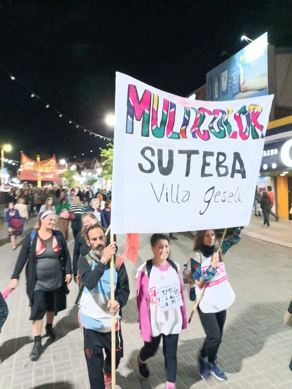 Militantes marchando de noche con la bandera MULTICOLOR en alto